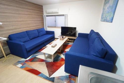 a living room with a blue couch and a table at Family Home Rinka Shitennoji RKA in Osaka