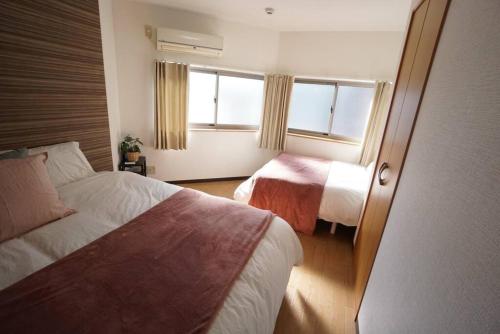 a hotel room with two beds and a window at Family Home Rinka Shitennoji RKA in Osaka