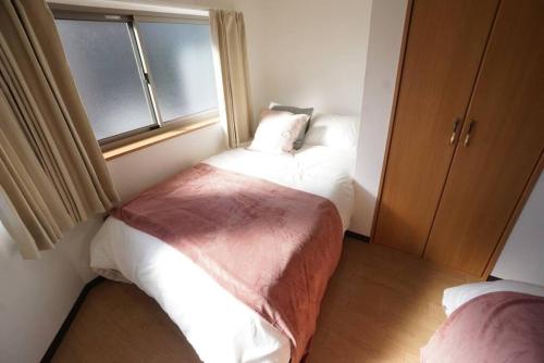 a small bedroom with two beds and a window at Family Home Rinka Shitennoji RKA in Osaka