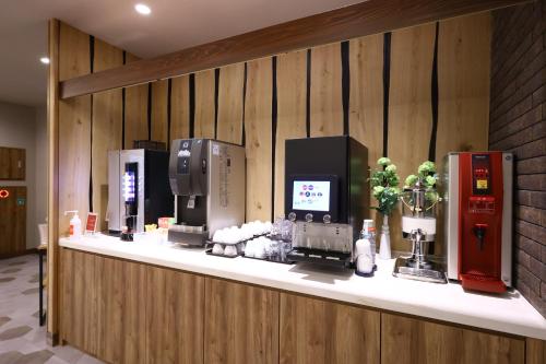 a counter with several appliances on a wooden wall at Dormy Inn Express Fujisan Gotemba in Gotemba