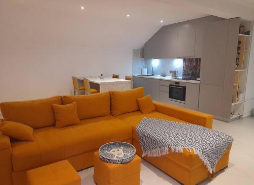 uma sala de estar com um sofá laranja e uma cozinha em Jan-Air em Ilinden