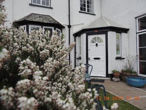 a house with a white door and a bush with flowers at Orchard House Hotel in Lynmouth