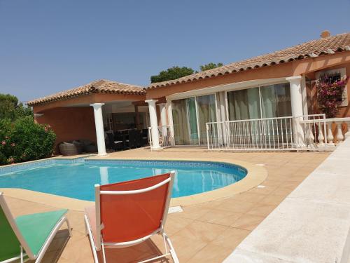 a swimming pool with two chairs and a house at Villa plain pied avec piscine privée 8 personnes in La Crau