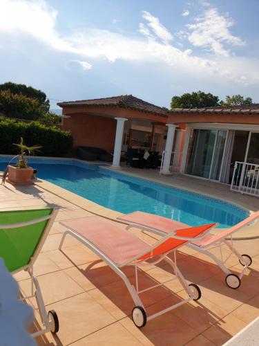 a swimming pool with two chairs and a house at Villa plain pied avec piscine privée 8 personnes in La Crau