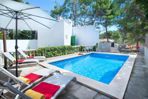 a swimming pool with chairs and an umbrella at Owl Booking Villa Mariner - 5 Min Walk to the Beach in Pollença