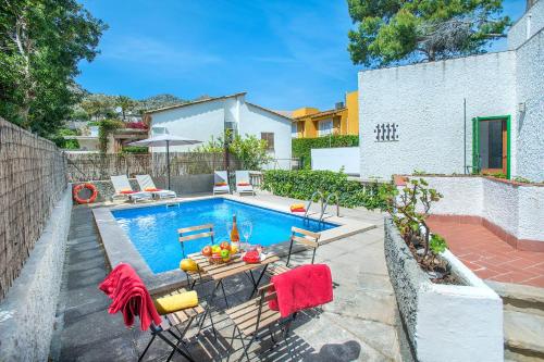 a pool with a table and chairs next to a house at Owl Booking Villa Mariner - 5 Min Walk to the Beach in Pollença