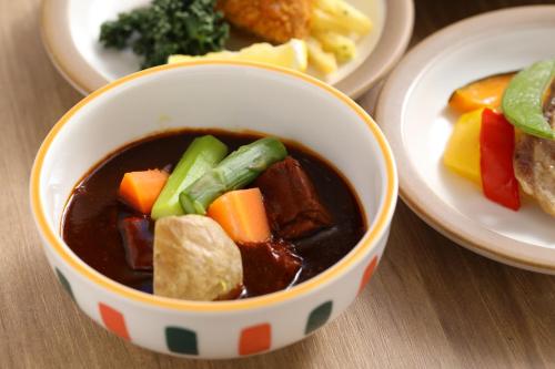 a bowl of soup on a table with plates of food at Dormy Inn Express Fujisan Gotemba in Gotemba