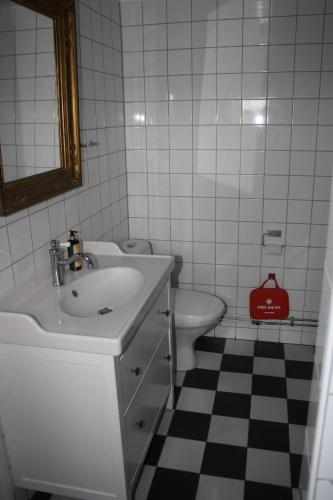 a white bathroom with a sink and a toilet at Ladugårdens Pub & Sal in Enhörna