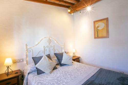 ein Schlafzimmer mit einem weißen Bett mit blauen Kissen in der Unterkunft Apartamento La Mesta, Facinas - Tarifa in Facinas