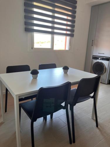 - une table et des chaises blanches dans une cuisine avec une fenêtre dans l'établissement Apartamento Luda, à Torreperogil