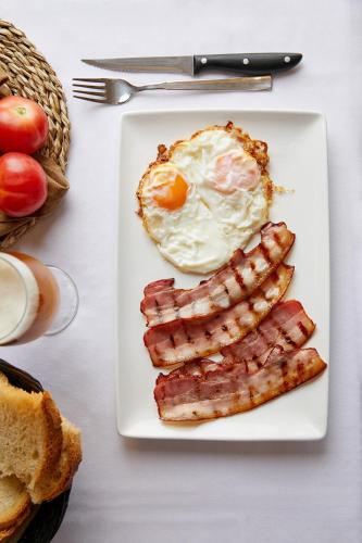 een bord met ontbijtproducten met eieren en spek bij Aparthotel Cal Marçal in Puig-reig
