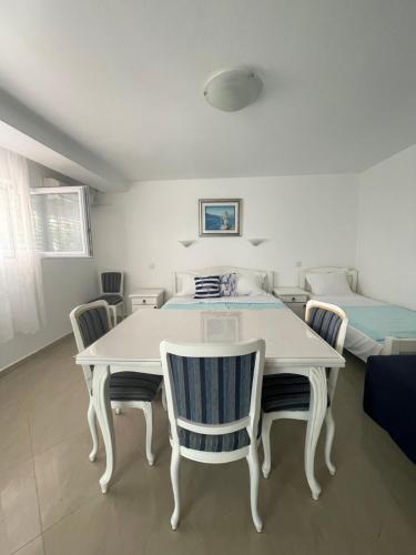 a white table and chairs in a room with a bed at Apartmani IVA Bečići in Becici