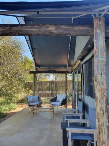 eine überdachte Veranda mit blauen Stühlen und einem Tisch in der Unterkunft Umkumbe Bush Lodge - Luxury Tented Camp in Skukuza