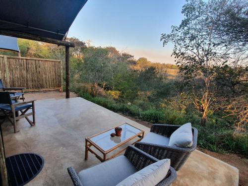 a patio with two chairs and a mirror on a table at Umkumbe Bush Lodge - Luxury Tented Camp in Sabi Sand Game Reserve