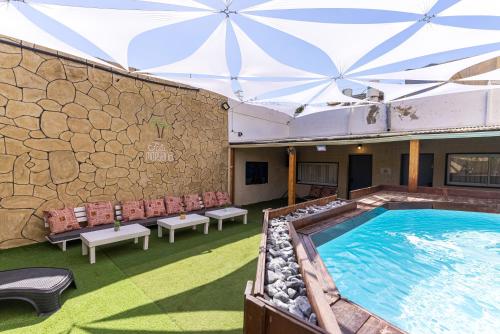 ein Hallenbad mit Liegestühlen und einer Steinwand in der Unterkunft פאטה מורגנה אואזיס - בית נופש פרטי עם בריכה מחוממת in Be’er Scheva