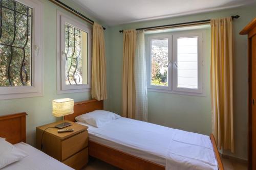 a bedroom with two beds and two windows at Korsan Apartment No.16 in Kaş