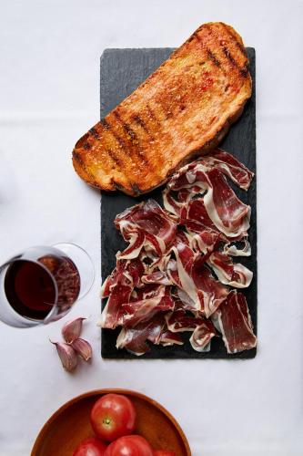 een bord met vlees en toast en een kom met fruit bij Aparthotel Cal Marçal in Puig-reig