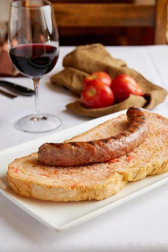 een bord eten met een worstje en een glas wijn bij Aparthotel Cal Marçal in Puig-reig