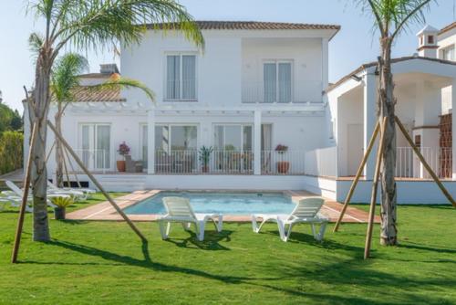 un patio con 2 sillas, una piscina y una casa en Villa Girasol en Benalup Casas Viejas