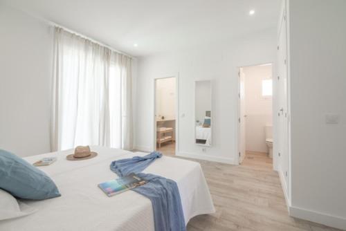 Un dormitorio blanco con una cama con una toalla azul. en Villa Girasol, en Benalup-Casas Viejas