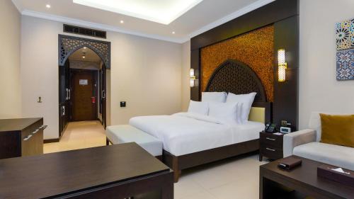 a hotel room with a bed and a living room at Grand Millennium Gizan in Jazan