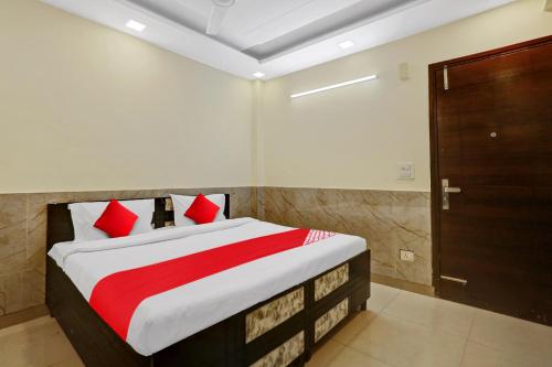a bedroom with a bed with red pillows and a door at Flagship Welcome Hotel Near Dlf Avenue Saket in New Delhi