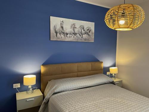 a bedroom with a bed with a blue wall and two lamps at Favolabella The Loft in Bardolino