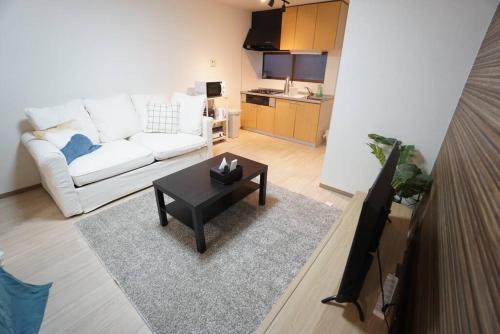 a living room with a white couch and a table at Family Home Rinka Shitennoji RKB in Osaka