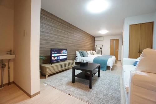 a bedroom with a bed and a tv and a couch at Family Home Rinka Shitennoji RKB in Osaka