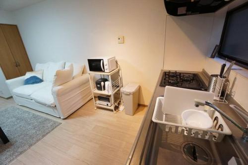 a small living room with a couch and a kitchen at Family Home Rinka Shitennoji RKB in Osaka