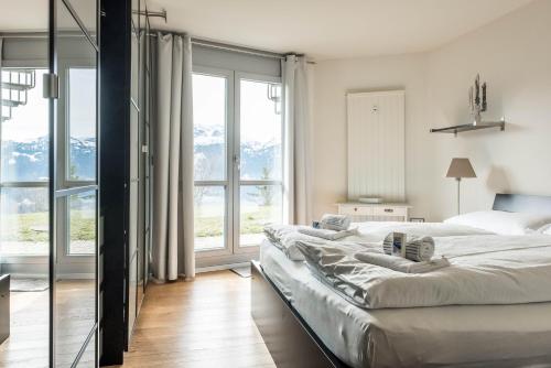 a bedroom with two beds and a large window at Apartment Alpenrose 2.5 mit Mitbenutzung SPA & Wellness - GRIWA RENT AG in Beatenberg