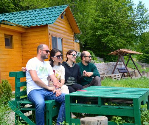 un grupo de personas sentadas en un banco frente a una cabaña en Kanach tun en Yenokavan