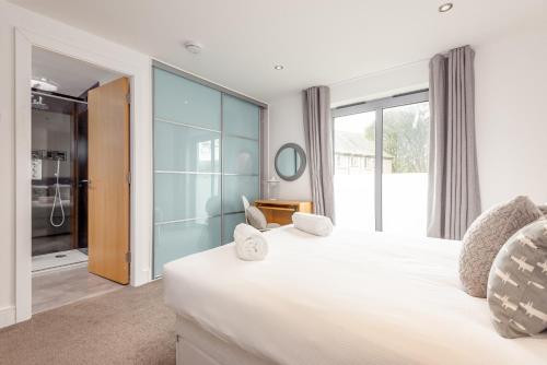ein Schlafzimmer mit einem großen weißen Bett und einer Glaswand in der Unterkunft Luxury Apartment with Balcony, Free Parking in St Andrews