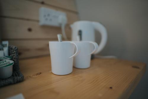 duas chávenas brancas em cima de uma mesa de madeira em Charnock Farm Motel em Leyland