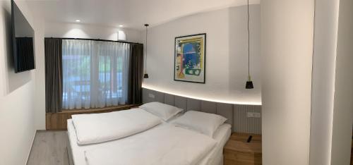 a white bed in a room with a window at Žigon Bed & Breakfast in Logatec