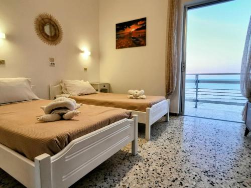 two beds in a room with a view of the ocean at Anatolikos Rooms in Alykes