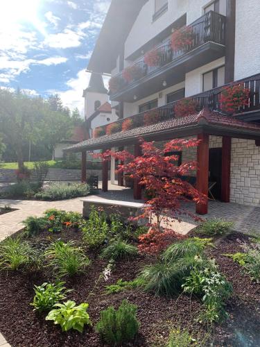 a building with a garden with red flowers in front of it at Žigon Bed & Breakfast in Logatec