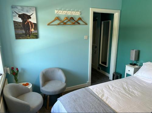 a bedroom with a bed and a chair and a picture of a cow at Castle View in Lochaline
