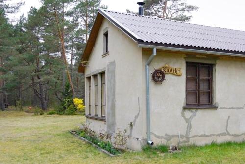 um pequeno edifício branco com um cartaz em Kadiķi em Ventspils