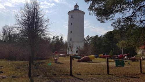 un phare avec une aire de jeux devant lui dans l'établissement Kadiķi, à Ventspils