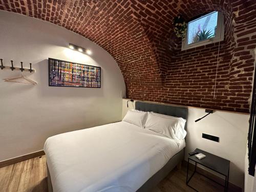 Cama en habitación con pared de ladrillo en PACOROOMS, en Madrid