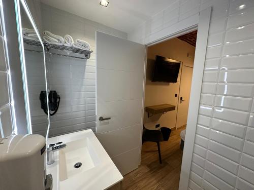 baño blanco con lavabo y teléfono en PACOROOMS, en Madrid