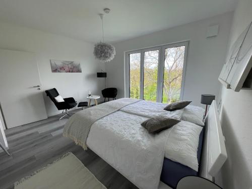 ein weißes Schlafzimmer mit einem Bett und einem großen Fenster in der Unterkunft Apartment mit Stil in Stuttgart