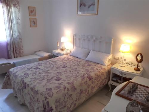 a bedroom with a bed and two tables and two lamps at El Capricho de Espartinas in Espartinas