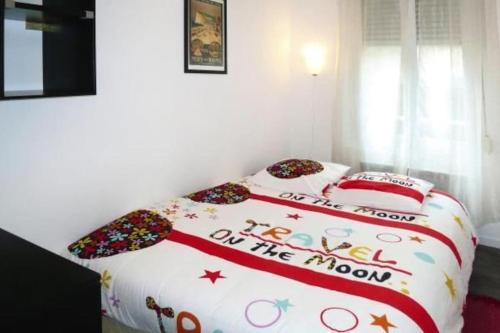 een bed met een rood en wit dekbed met de woorden blij op bij Nid douillet pour 2.. à 50 mètres de la plage in Mers-les-Bains