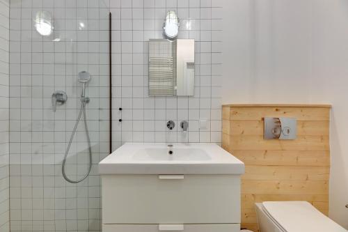 a white bathroom with a sink and a shower at Staywin WILCZA apartments in Gdańsk