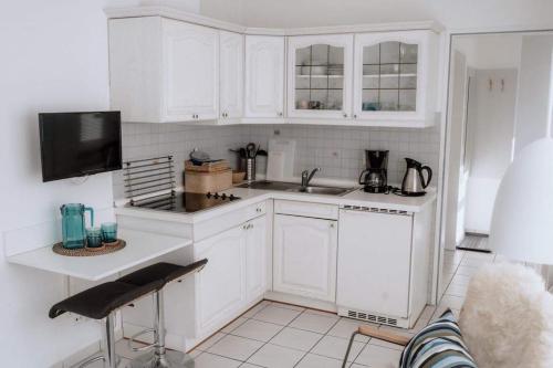 a kitchen with white cabinets and a sink at Haus Sandröschen in Norderney