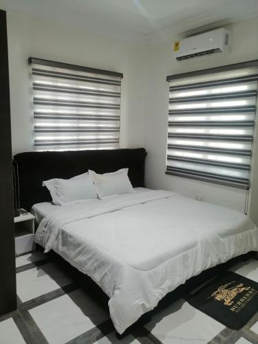 a bed with white sheets and pillows in a bedroom at Terra Santa Lodgings in Accra