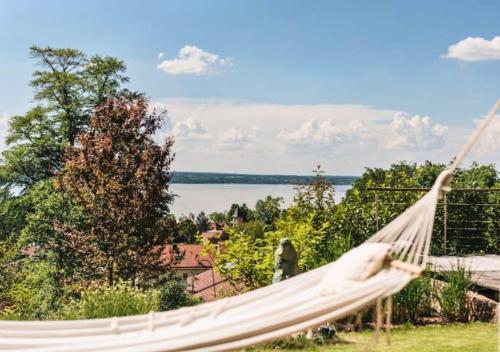 a hammock on a patio with a view of the water at Snug Stays - Traumhafter Seeblick, 2 Zi Apartment, Garten & Terrasse in Herrsching am Ammersee