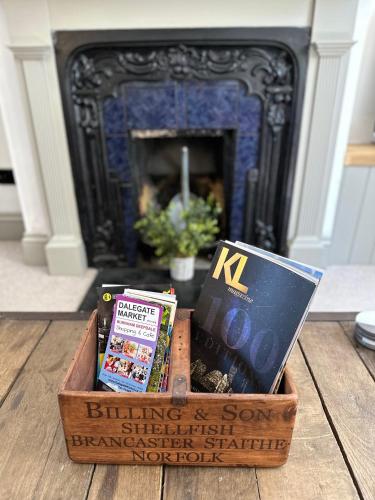 a basket of books sitting on a table in front of a fireplace at Quayside Georgian Townhouse in Kings Lynn